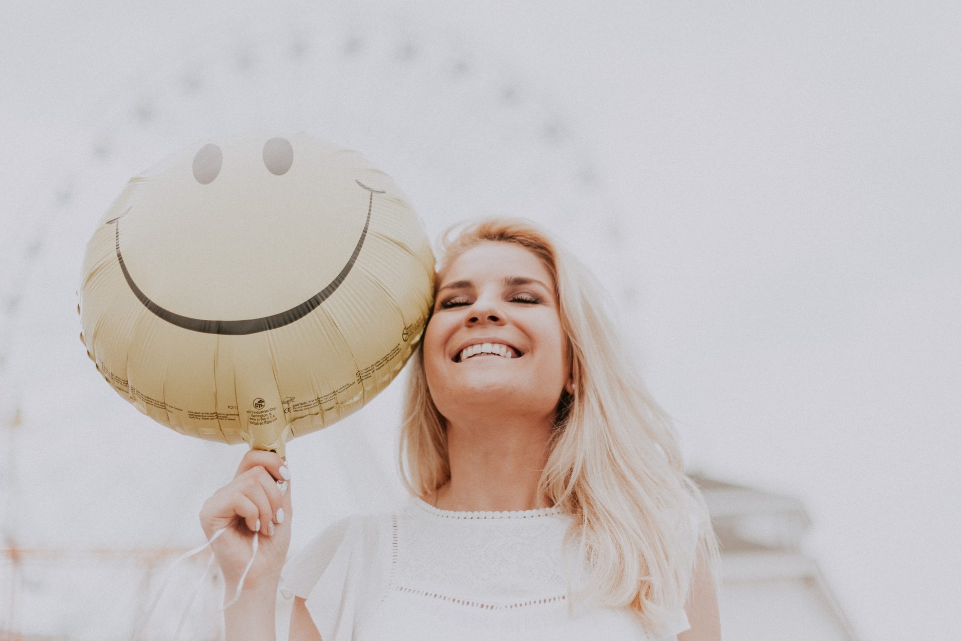 Lächelnde Frau mit Smiley-Luftballon